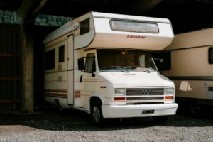 Camping-car blanc « Eleanor » sous un toit métallique sur un sol de gravier.